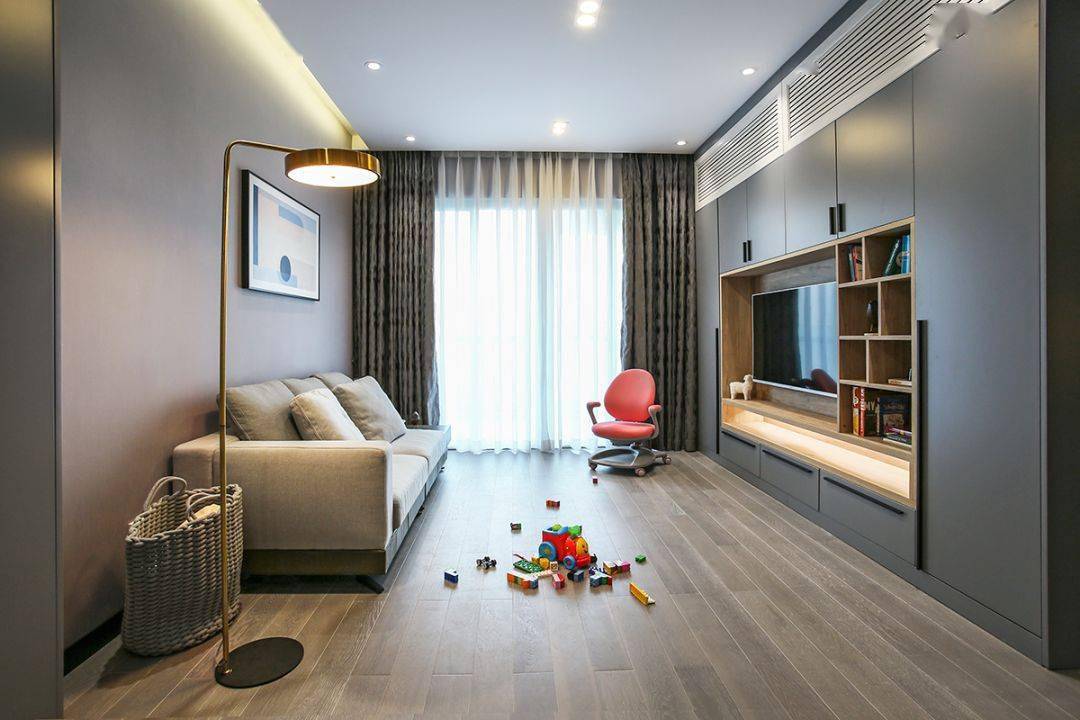 今天分享的是一套建筑面積102平米的現(xiàn)代輕奢風(fēng)三居室案例，屋主夫妻和女兒、母親一家四口人居住，整體來說是比較緊湊的剛需三房案例，設(shè)計(jì)師以輕松、時(shí)尚的灰色調(diào)作為主色，搭配格調(diào)滿滿的木質(zhì)家具，營(yíng)造出簡(jiǎn)約、輕奢的感覺。    平面布置圖    入戶玄關(guān)和餐廳連在了一起，利用了入戶門側(cè)方的墻面來做上一整墻的柜子，把鞋柜和餐邊柜結(jié)合在一起使用，更為省空間。    復(fù)古的木質(zhì)餐桌椅到灰色調(diào)的背景，金屬質(zhì)感的吊燈，整個(gè)餐廳看起來非常有格調(diào)感。在餐桌椅側(cè)方加上隔板的設(shè)計(jì)，增強(qiáng)儲(chǔ)物能力。    位于餐廳另一側(cè)的就是客廳空間了，客廳的茶幾被舍棄，中間留空方便作為孩子的娛樂區(qū)，米色布藝沙發(fā)和暖灰色背景墻讓人感覺更加溫馨。    客廳的電視背景墻則是被利用起來做了收納，整墻的柜子留空電視周邊的部分區(qū)域，加上藏光之后使用更方便，看起來也更大氣。    廚房?jī)?nèi)部的櫥柜延續(xù)了客餐廳的柜子顏色，深灰色的大理石墻磚搭配灰色的啞光地磚，整個(gè)廚房看起來很有現(xiàn)代感。    臥室選擇了以藍(lán)灰色為主，在臥室頂部吊頂內(nèi)加上藏光，用吊燈、臺(tái)燈等代替主燈，讓臥室看起來更為簡(jiǎn)潔。    在主臥室里還有一個(gè)迷你的衣帽間，U字形布局的柜子把角落空間充分用上。衣帽間外的床頭柜改成了梳妝臺(tái)，使用起來更加方便。    老人房選擇了榻榻米床組合衣柜和書桌的設(shè)計(jì)，榻榻米的安全性會(huì)更高一些，加上一張書桌也方便屋主母親看看書。    衛(wèi)生間內(nèi)部是三角形的布局方案，鉆石形的淋浴房做在了轉(zhuǎn)角處，兩側(cè)擺放洗手臺(tái)和馬桶。洗手臺(tái)上方的鏡柜做了藏光的設(shè)計(jì)，看起來更時(shí)尚。